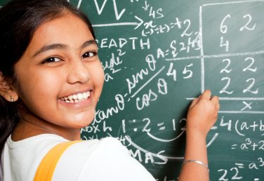 girl practising elementary math on chalkboard